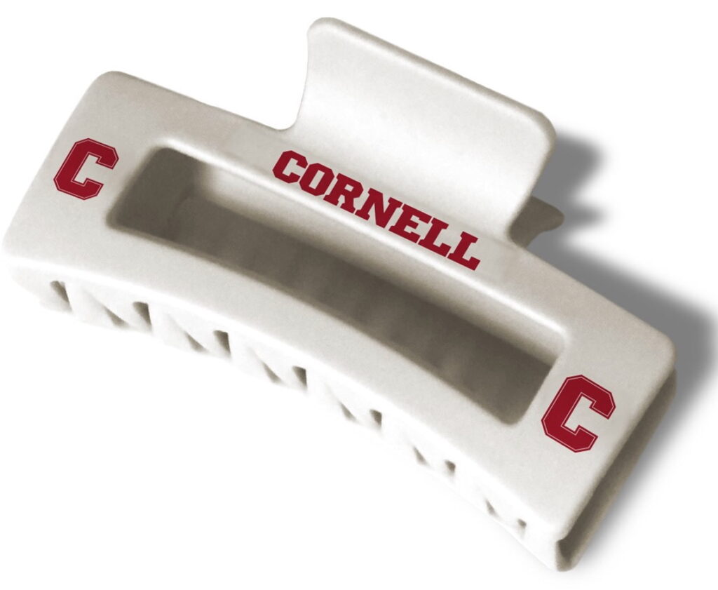 A white claw clip for hair with red "Cornell" and "C" logos on it.