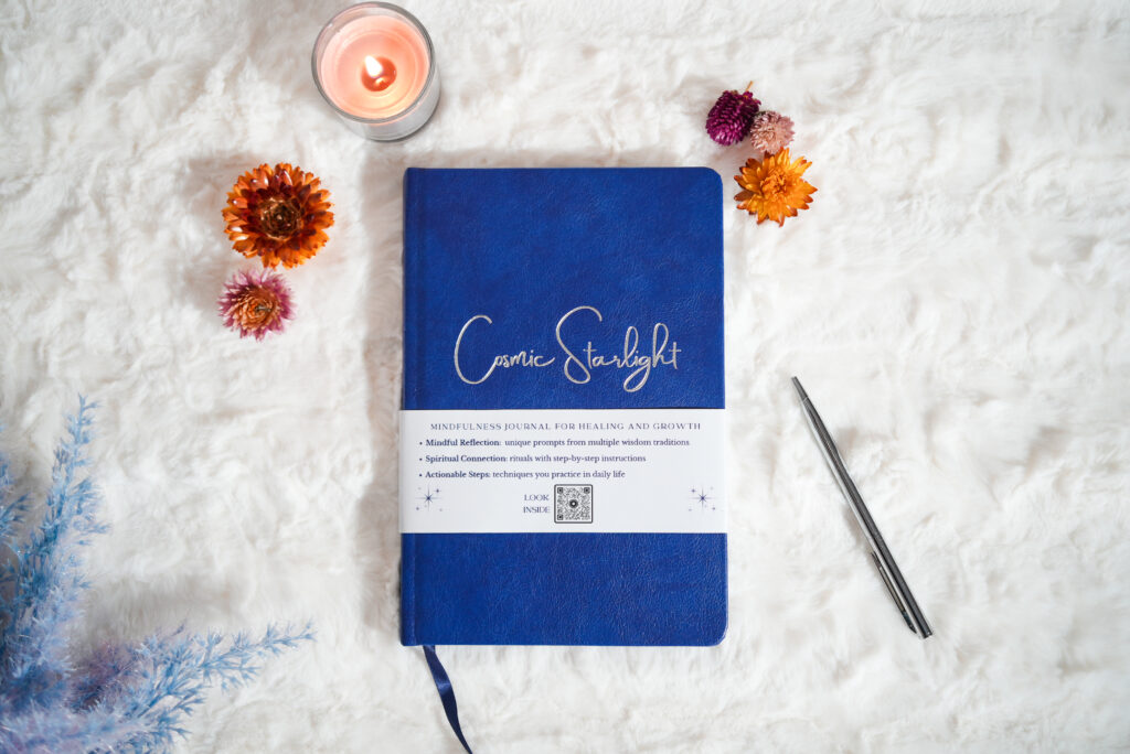 A blue journal titled Cosmic Starlight on a snowy background with flowers and a votive candle