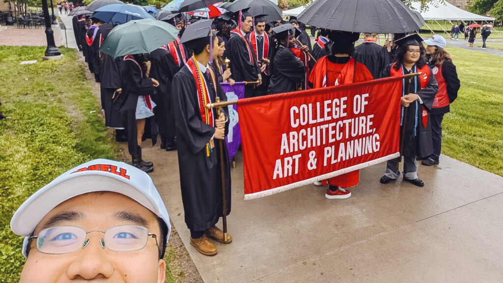 Tony Chen in front of the AAP banner at Commencement