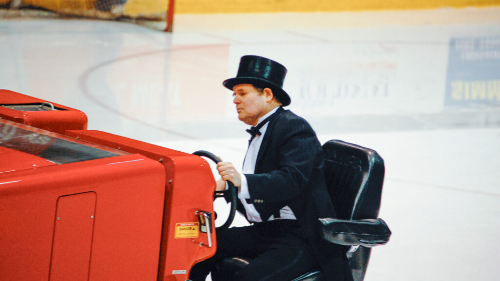 Dave Nulle driving an ice resurfacer at Lynah Rink, dressed in top hat and tails