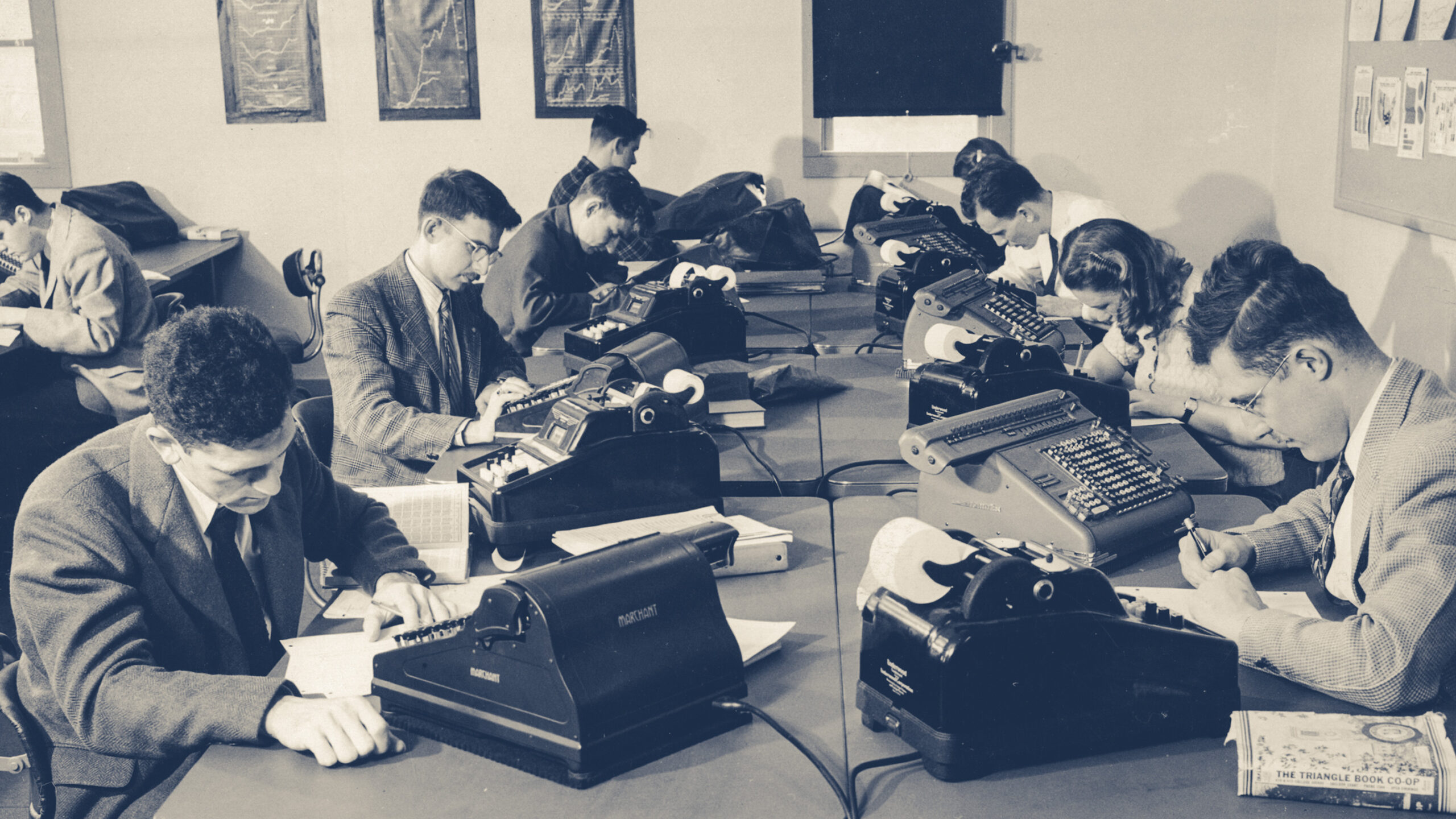 Students work with adding machines and pencils and paper in a statistics class in 1947