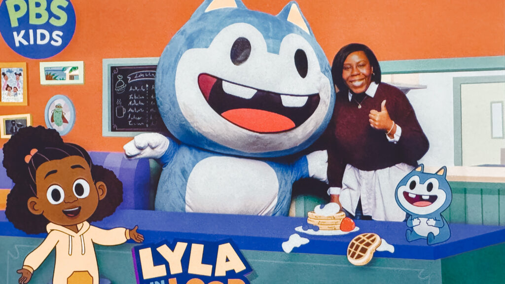 Monique Hall smiles and gives a thumbs up with the characters from Lyla in the Loop.