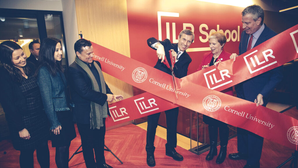 then ILR Interim Dean Alex Colvin, center, prepares to cut the ribbon at the open house for the new ILR and Cornell hub in Manhattan in 2019; with him are, from left, Jamie Morganstern ’18, Samantha Falchook ’18, Russell Hernandez ’88, New York State Labor Commissioner Roberta Reardon and New York City Mayor Bill de Blasio.