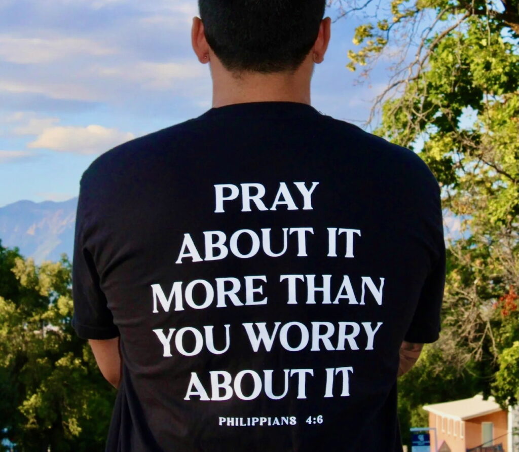 A man wearing a T shirt with a slogan on the back that says "Pray about it more than you worry about it" Philippians 4:6