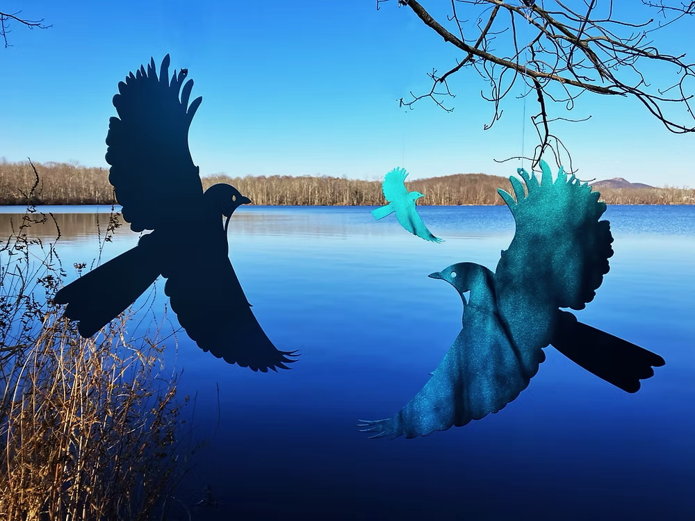 metal sculptures of bluebirds by a lake