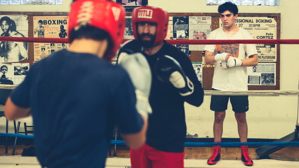 Will MacLeod stands outside of the ring and watches two boxers training at the Greater Ithaca Activities Center.