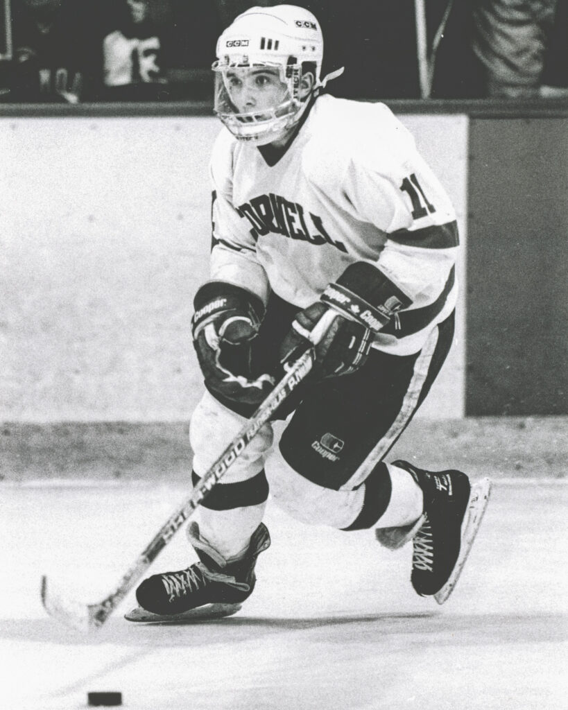 Doug Derraugh as a player for the Big Red in uniform, skating with the puck in possession.