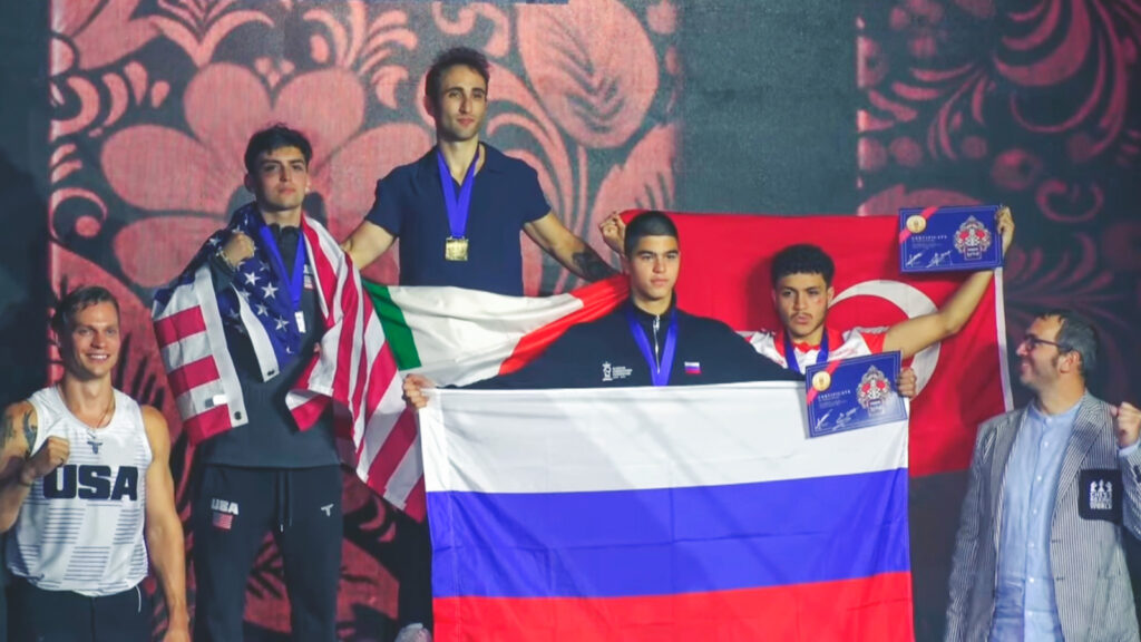 Will MacLeod stands with the other medalists at the chess boxing world championship as everybody holds their country's flags.