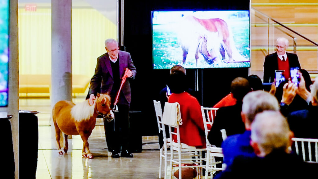 President Mike Kotlikoff escorts Minnie into a trustee dinner event in May 2025