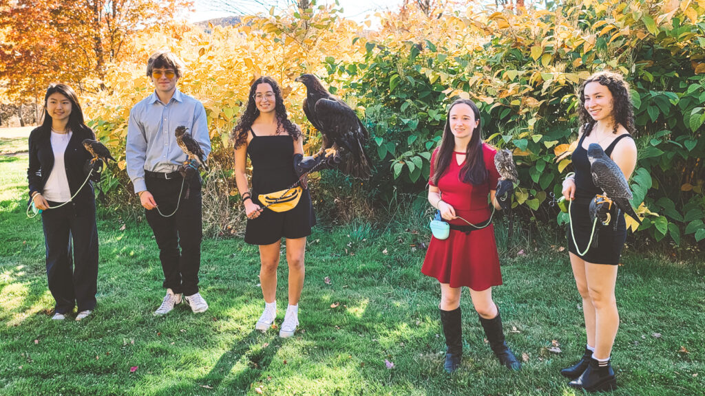 Five student handlers stand outside each with a raptor on a lead.