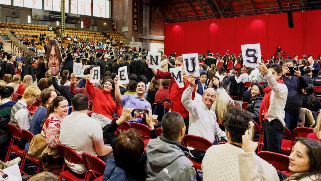 Audience members hold up signs celebrating a graduate during the December 2025 recognition ceremony in Barton Hall