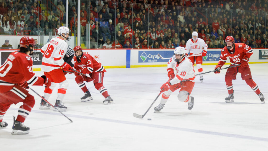 Cornell hockey player Jake Kraft skates down the ice as Harvards defense surrounds him.