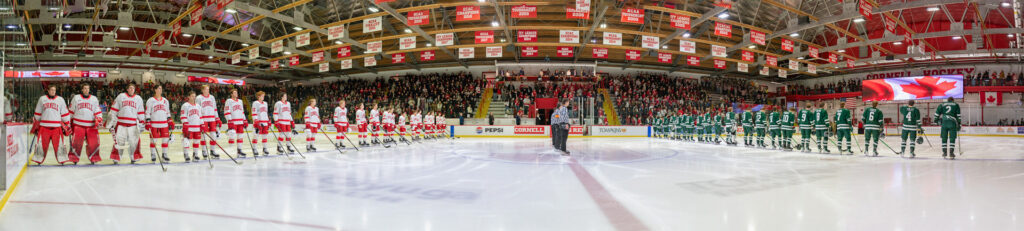 Cornell and Dartmouth players stand in a line on opposite sides while the Canadian national anthem plays.