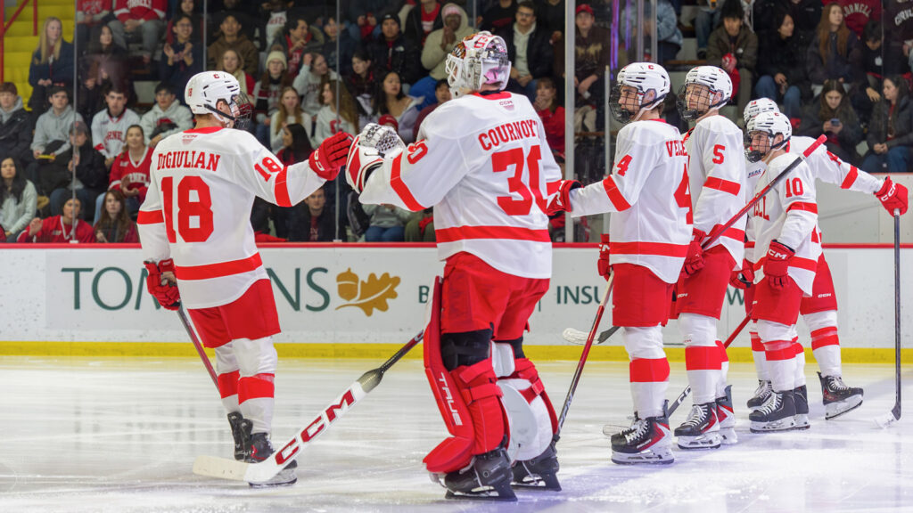 Cornell men's hockey players high five each other in a line at the start of the game.