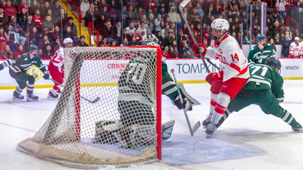 A Cornell hockey player in action shooting a goal against Dartmouth.