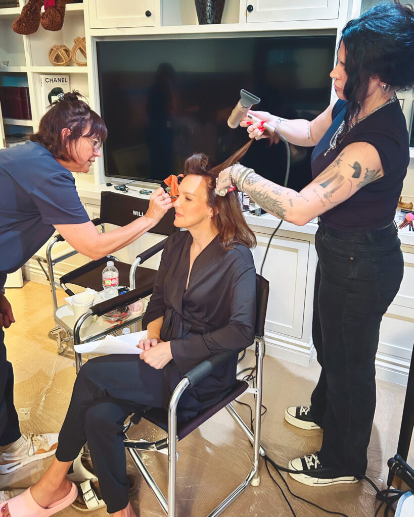 Carla Gallo sits in a chair while she gets her hair and makeup done.