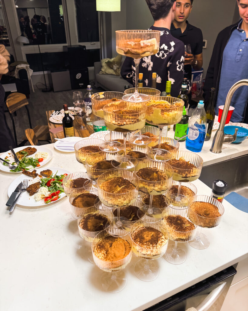 Pudding desserts in coupe glasses stacked into a tower sitting on an apartment kitchen counter.
