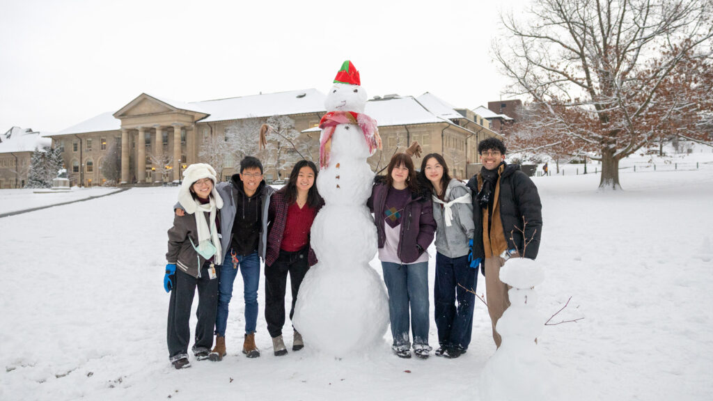 Six students pose with their snowman on the Arts Quad