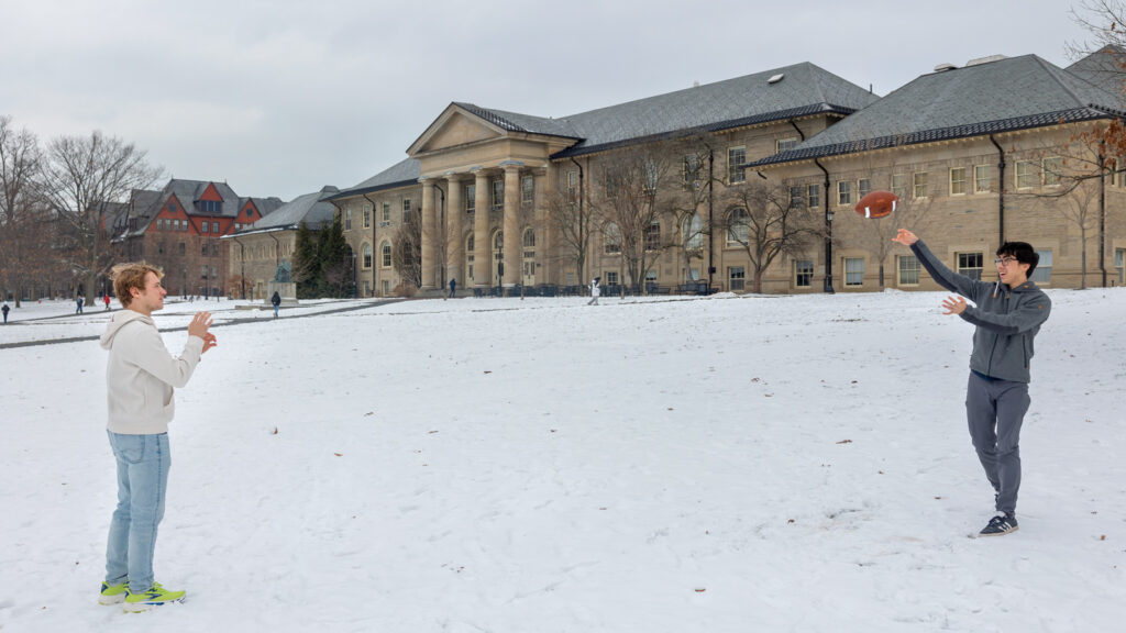 Students play football on the Arts Quad in the snow