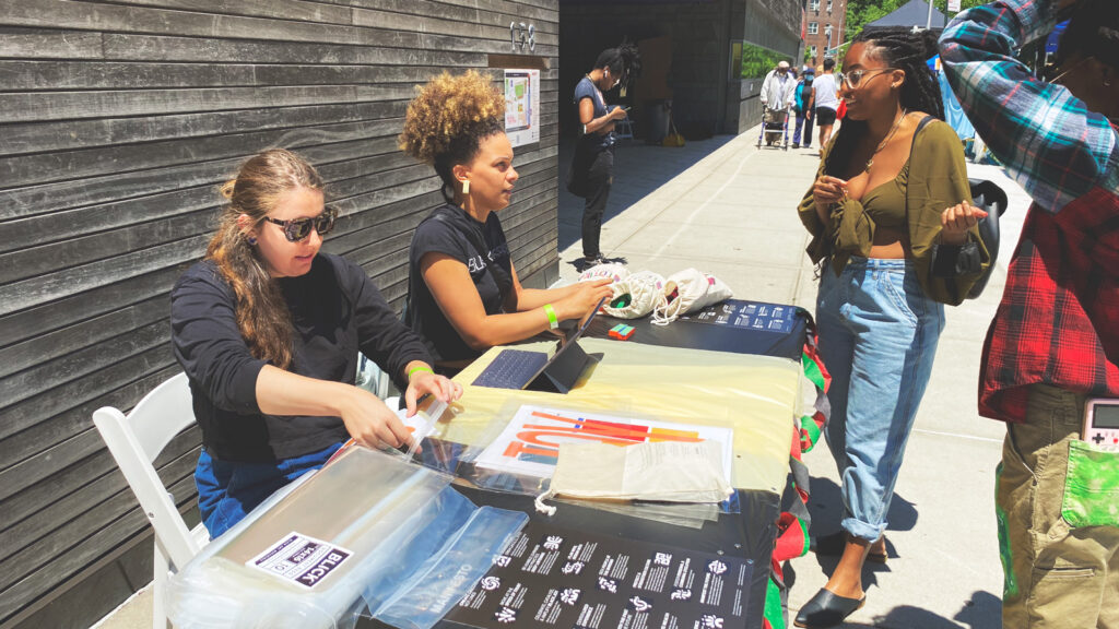 Emma Osore and another BlackSpace staffer give out information while tabling during a Juneteenth celebration in 2019