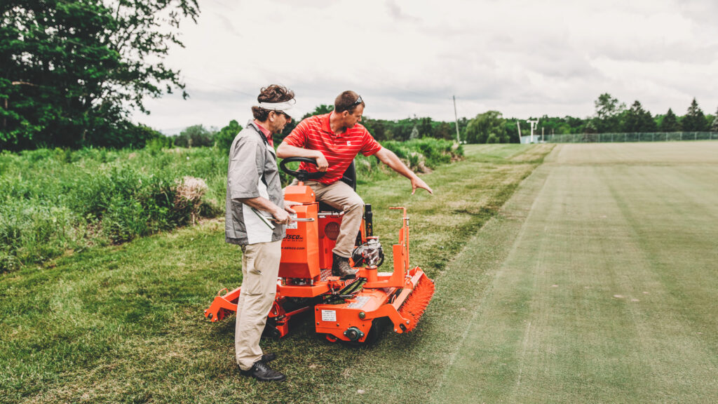 Professor Frank Rossi speaks with a staffer on a ride-on turf mower during research trials at the Bluegrass Lane Turf and Landscape Research Center in 2018