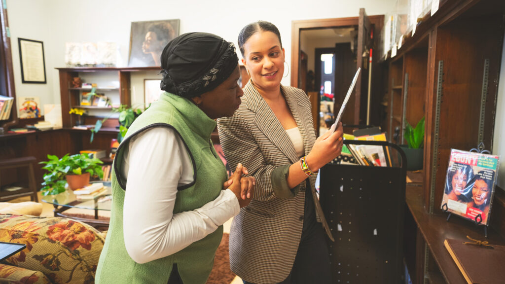 Emma Osore, right, examines a historic Black magazine at Brownsville Heritage House with Miriam Robertson, executive director of BHH