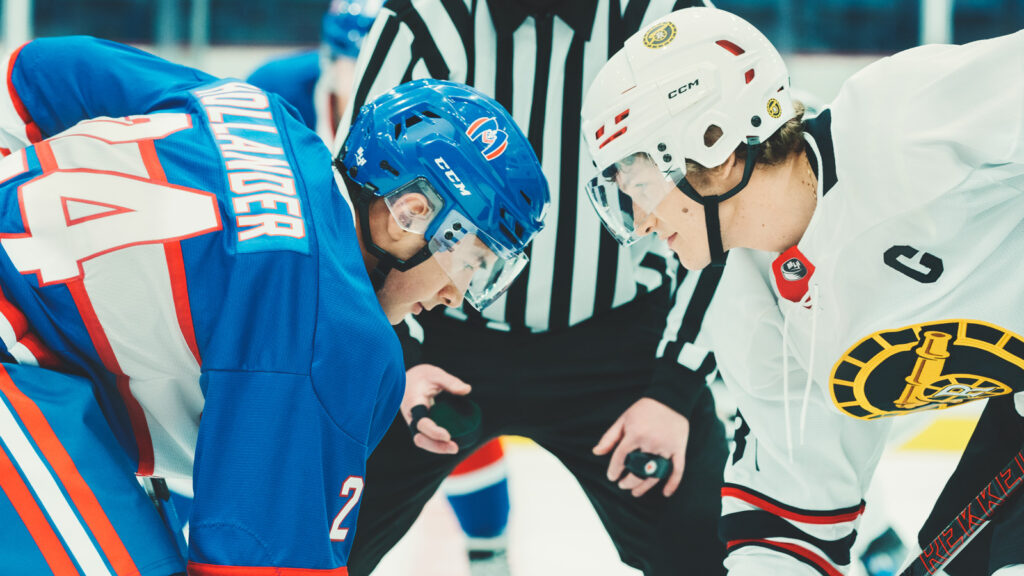 Heated Rivalry (L to R) - Hudson Williams as Shane Hollander and Connor Storrie as Ilya Rozanov in Episode 104 of Heated Rivalry. The two are in a hockey face-off.