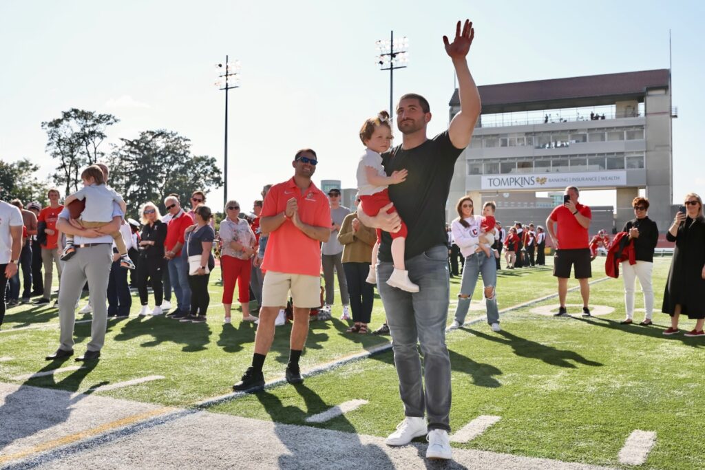 JC Tretter holds his toddler daughter and waves to the crowd during halftime on Schoellkopf Field