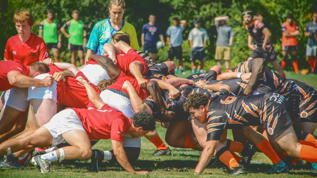 Cornell Men's Rugby players line up in the middle of the pitch head to head with their opponent.