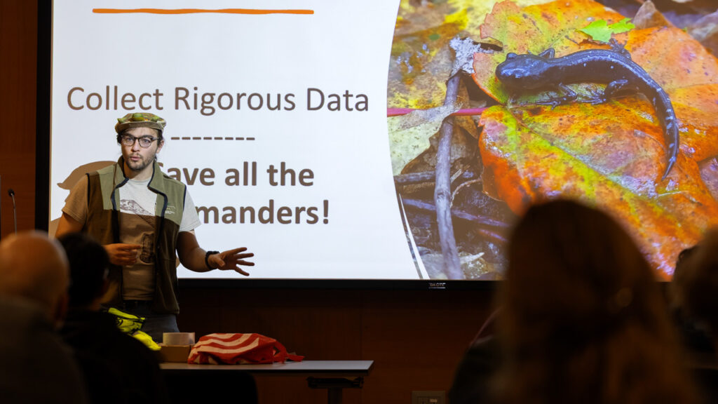A TCAMP leader in front of a slide screen that says "Collect Rigorous Data -- Save all the salamanders!"