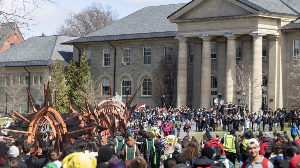 The dragon is paraded towards Goldwin Smith Hall while hundreds walk around it during Dragon Day 2026