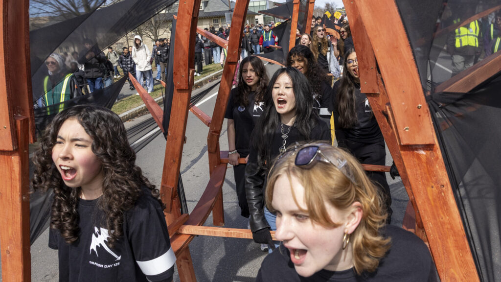Students cheer underneath the dragon while they parade it down the street during Dragon Day 2026