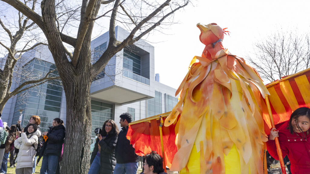 Students with the red, orange, and yellow phoenix next to Duffield Hall during Dragon Day 2026