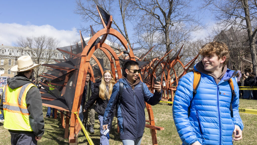 A line of students walk underneath the dragon after it has arrived on the Arts Quad at Dragon Day 2026