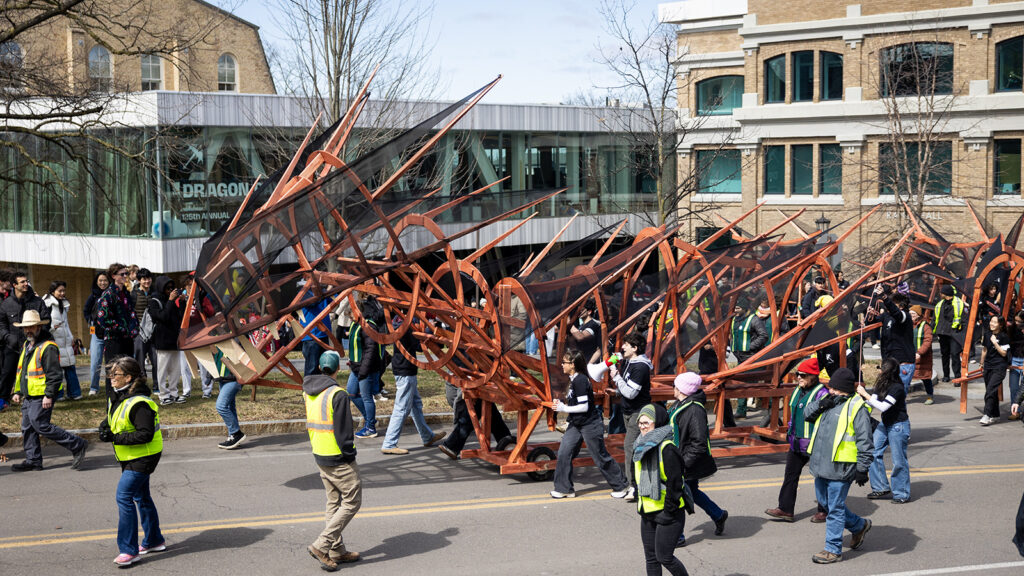 Students parade the orange, wooden dragon past Rand and Milstein halls at the start of Dragon Day 2026