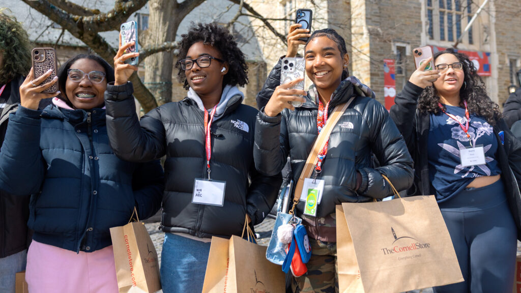 Four students hold their phones to take photos at Dragon Day