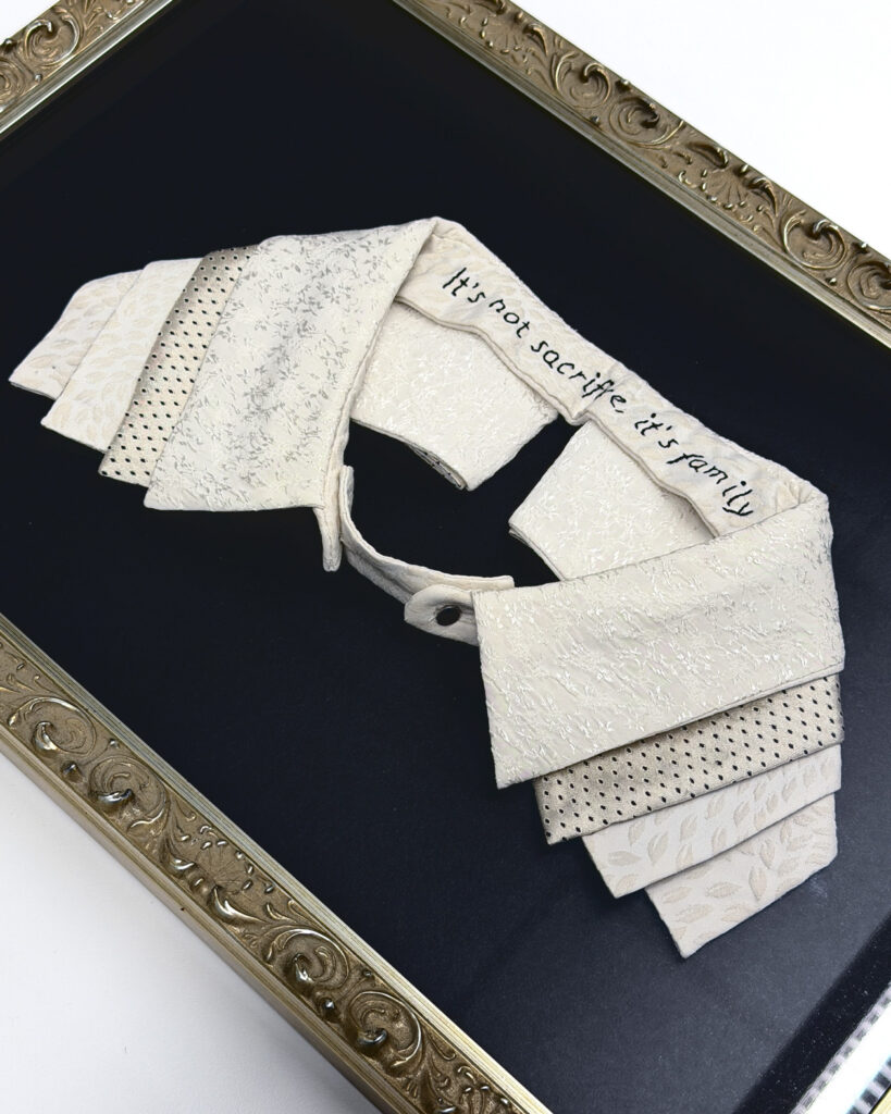 A white collar embroidered with the phrase, "it's not sacrifice, it's family"