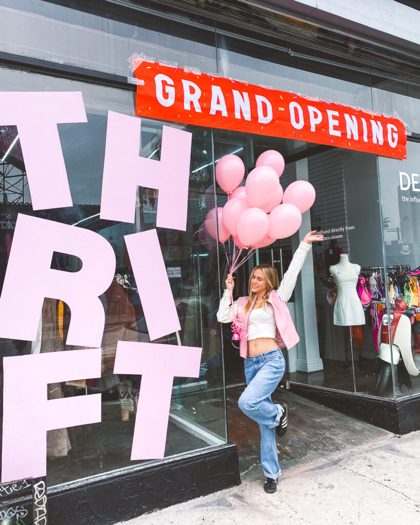 Meghan McKenzie Russell holding light pink balloons and posing outside the Detoure store during the grand opening.