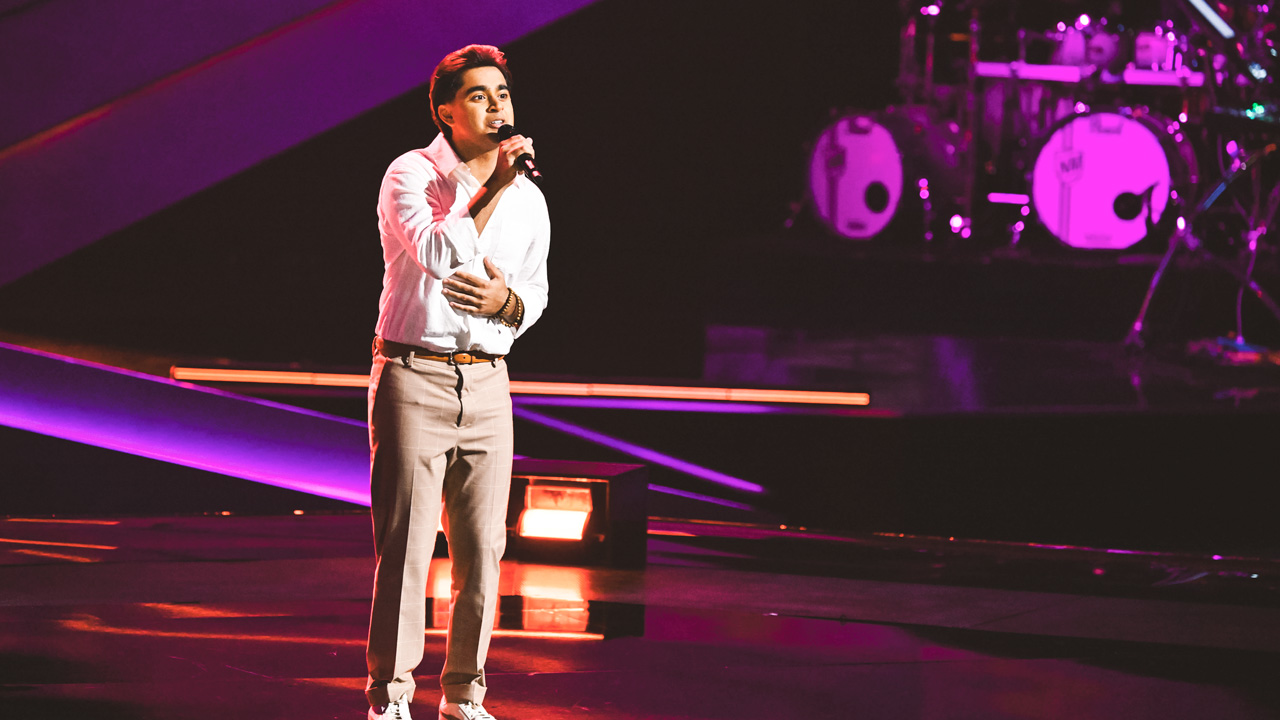 Adi Arora singing on stage during his blind audition on "The Voice."