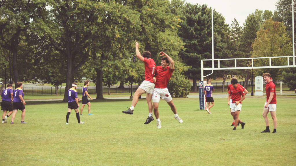 Two players jump in the air together during a celebration on the pitch.