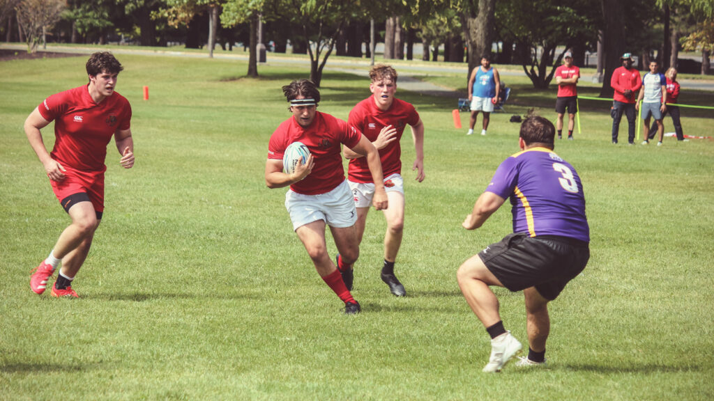 Thomas Duver runs with the ball with two teammates while trying to dodge an opponent.