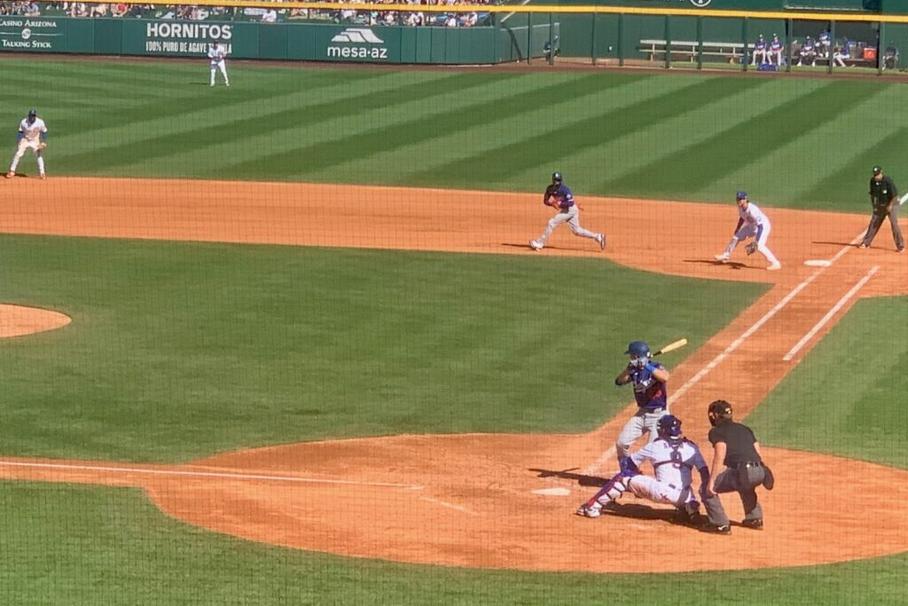 A batter at the plate at a MLB spring training game with a runner passing first base