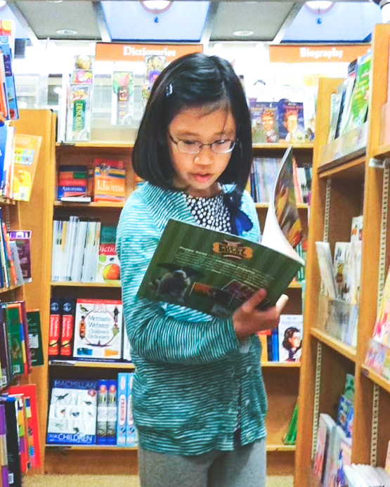 Serin Koh reading as a child, holding a book in a bookstore