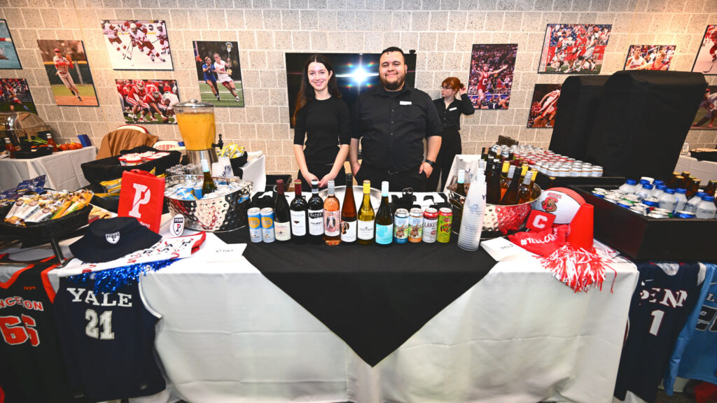 Two people behind a table offering adult beverages