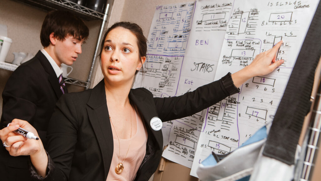 a student manager goes over back-of-the-house plans and seating and serving charts for a gala dinner at Hotel Ezra Cornell 2013
