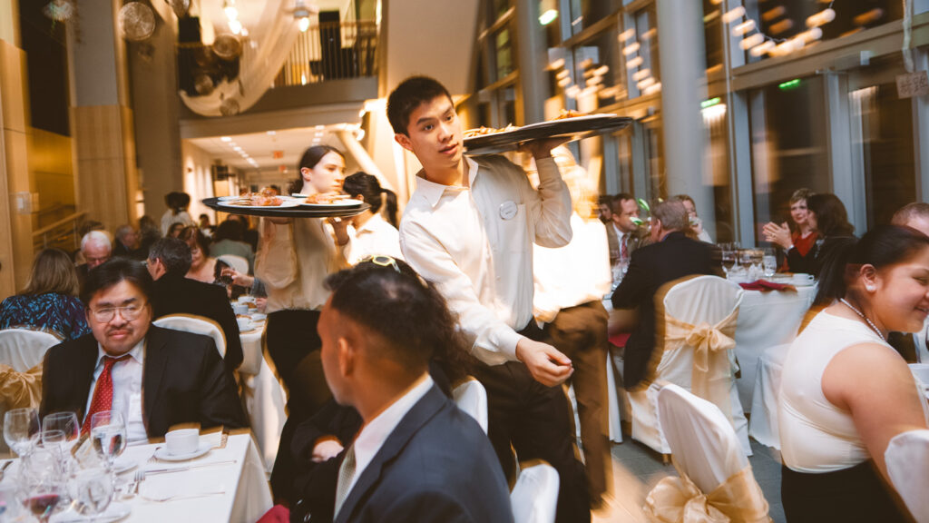 student waitstaff carry trays during a dinner event at Hotel Ezra Cornell 2011