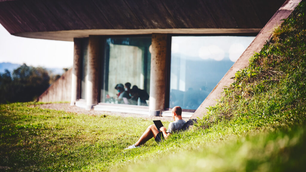 A student sits in the grass and studies outside Uris Library