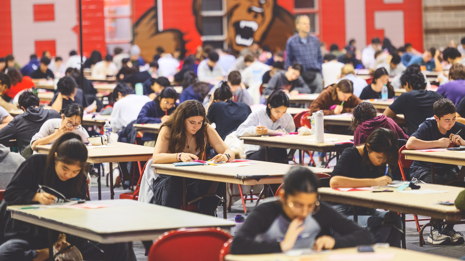 Dozens of tables with students sitting taking exams inside Barton Hall