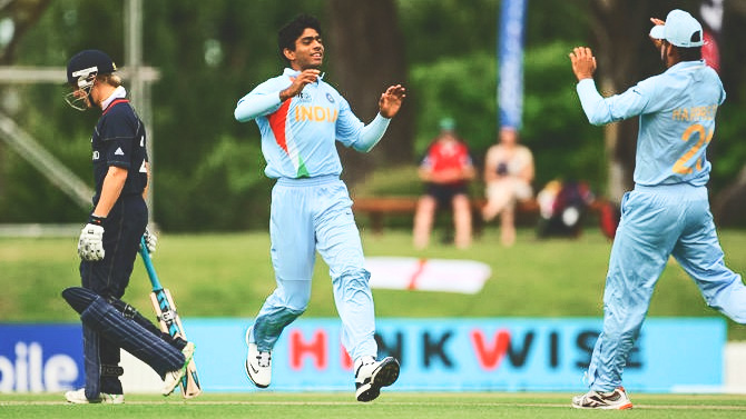 Saurabh Netravalkar, playing for India, runs to give a teammate a high five.