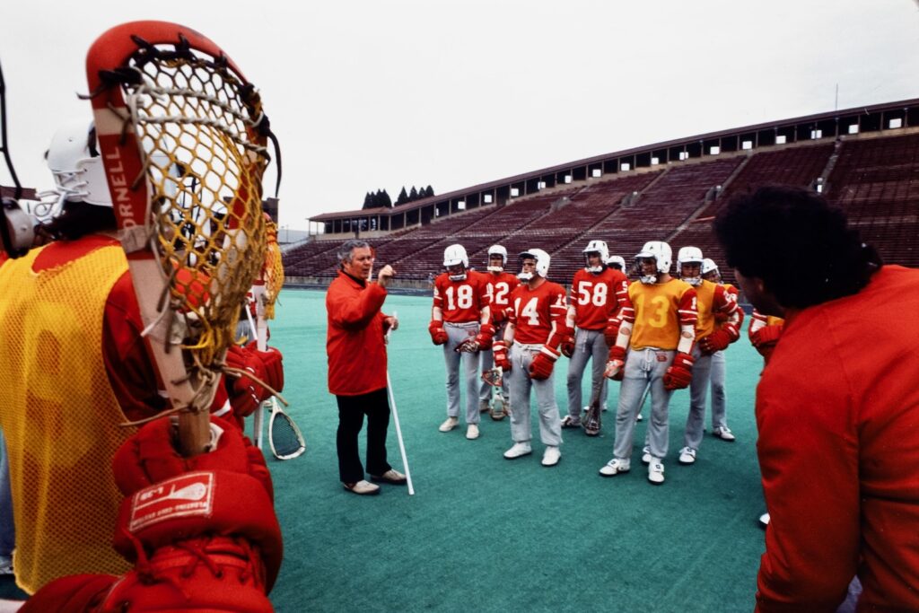 Big Red men's lacrosse coach Richie Moran speaks to team members at Schoellkopf Field in spring 1984